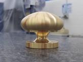 A full frontal view of a machined brass mushroom knob
