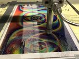 A side view showcasing a holographic sheet being worked on by a high pressure waterjet