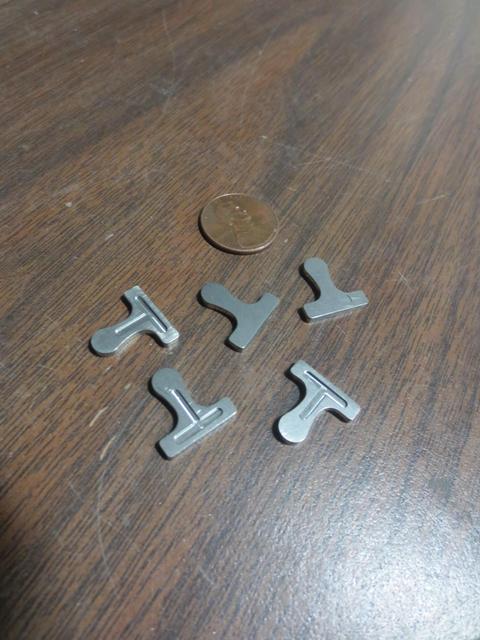 Examples of FedTech's machined stainless steel parts laying next to a penny