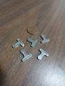Examples of FedTech's machined stainless steel parts laying next to a penny