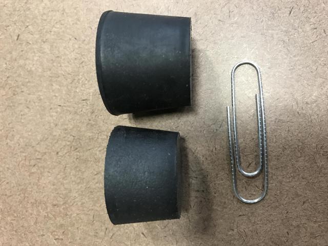 Two rubber stoppers sit beside a paper clip
