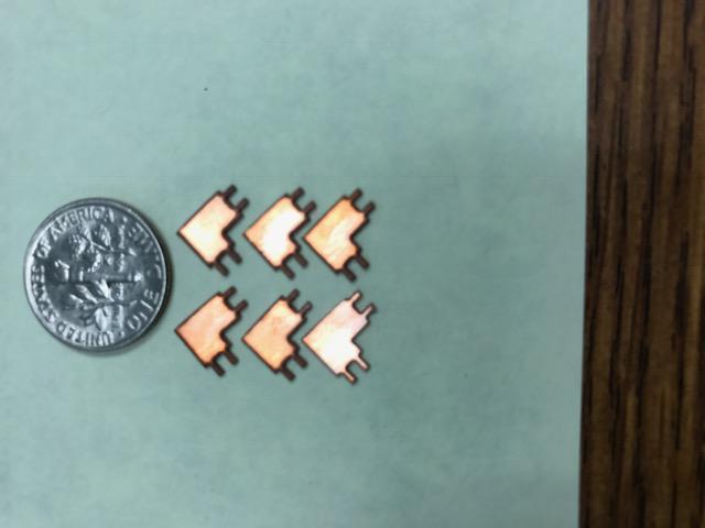 A zoomed in view of alloy 110 copper parts sitting next to a dime.