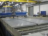 Aluminum plates sit on top of a machine bed waiting to be cut